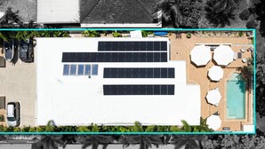 Un edificio con pannelli solari sul tetto, una piscina e un'area salotto esterna.