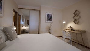 Ein Hotelzimmer mit Bett, Schreibtisch, Stuhl, Lampe und Spiegel.