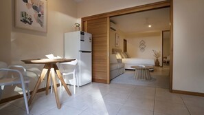 A modern living space with a dining area, a sofa, and a kitchen area.
