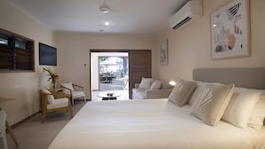 Una camera d'albergo con un letto grande, un'area salotto con sedie, un tavolo da pranzo e vista sull'esterno.