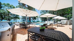 An outdoor patio with a pool, umbrellas, and seating areas.