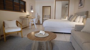 A hotel room with a bed, a desk, a chair, and a round coffee table.