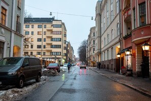 Calle con edificios a ambos lados, una furgoneta estacionada a la izquierda y una persona caminando.