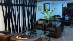 A lobby with leather sofas, a glass coffee table, and a decorative wall with vertical lines. - Carliza Hotel Lekki (Lekki)