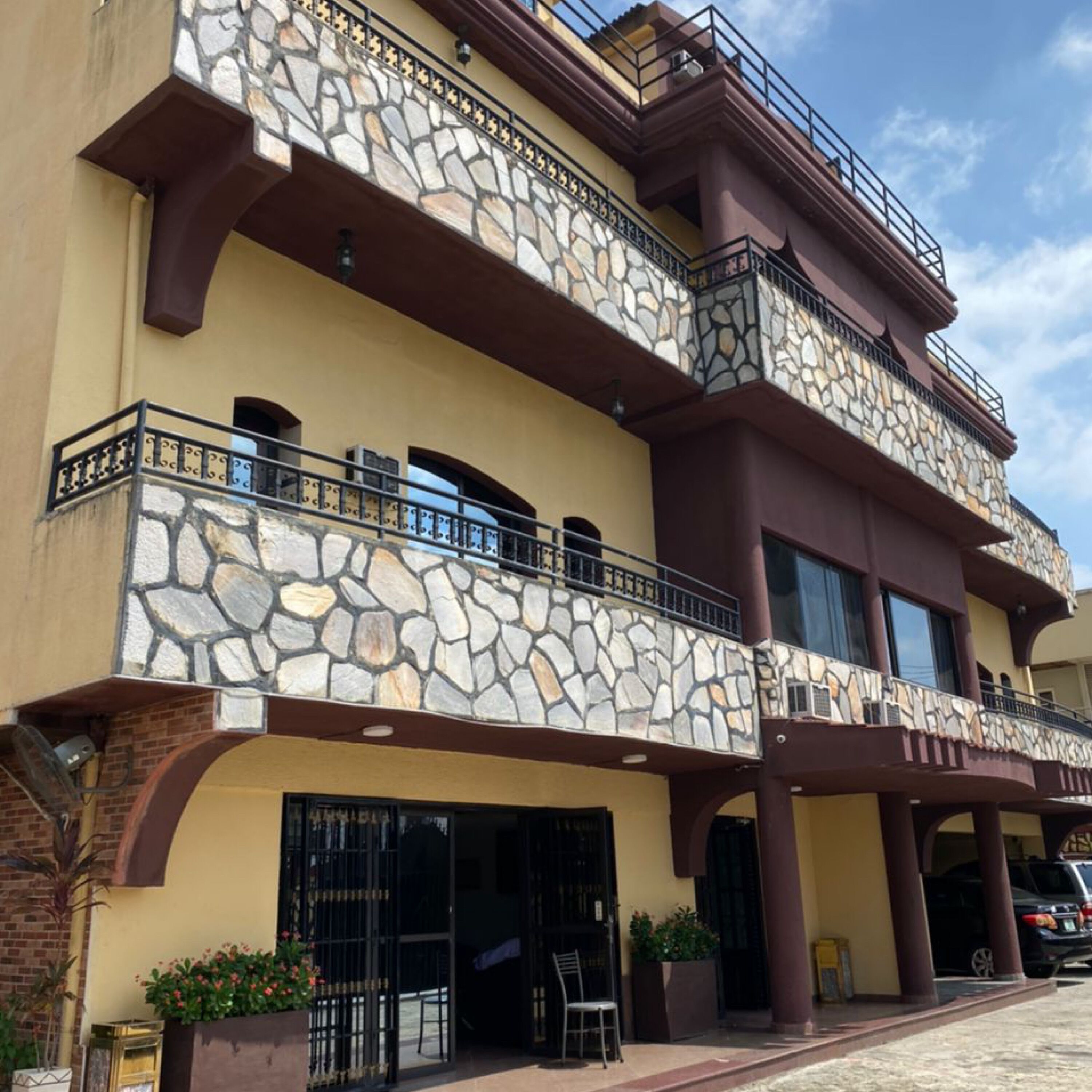 A multi-story building with a stone facade, balconies, and a gated entrance.