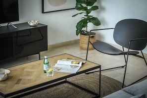 A modern living room with a coffee table, a magazine, a bottle, and a glass. - Mamad Luminous 3BR Escape with Balcony by SeaNRent (Tel Aviv)