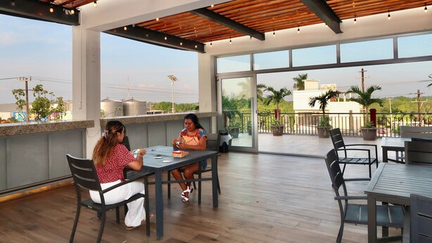 An outdoor patio area with wooden flooring, large windows, and modern furniture. - Hotel Yorio Inn (Tuxpan)