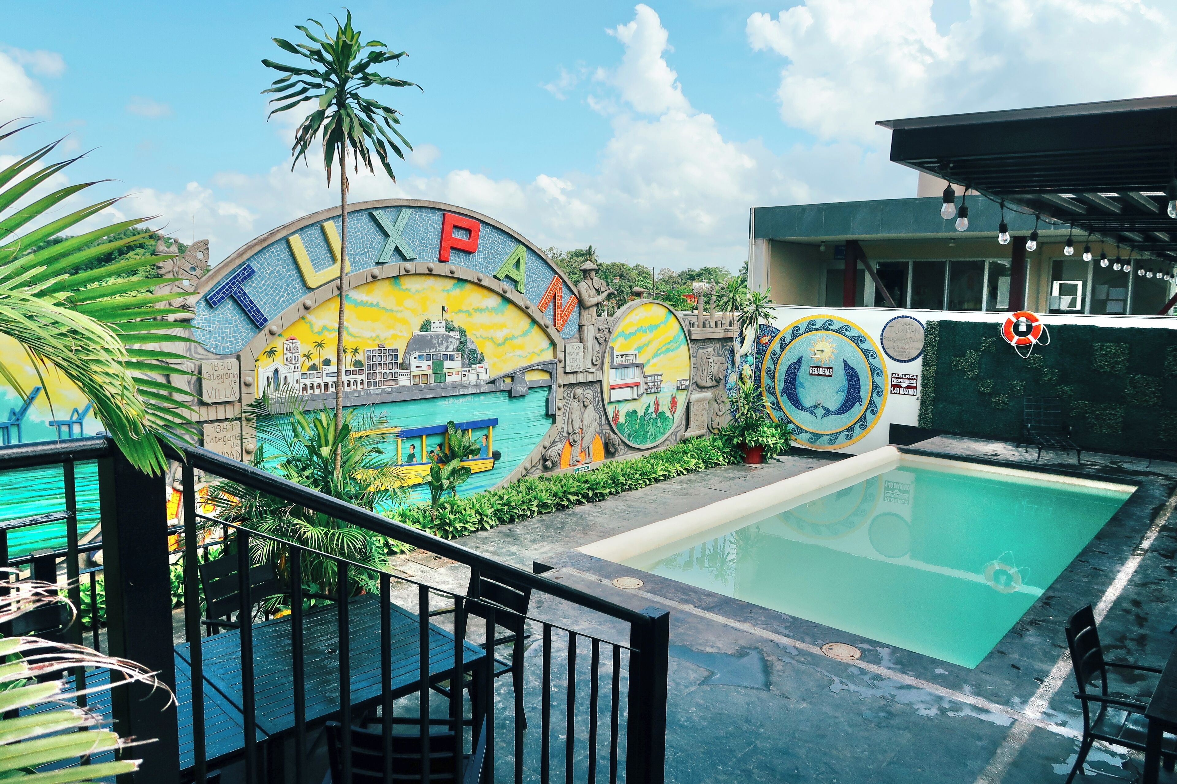 A swimming pool area with a mural depicting a cityscape and palm trees.