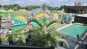 A view of a swimming pool area with a mural of a cityscape and palm trees. - Hotel Yorio Inn (Tuxpan)