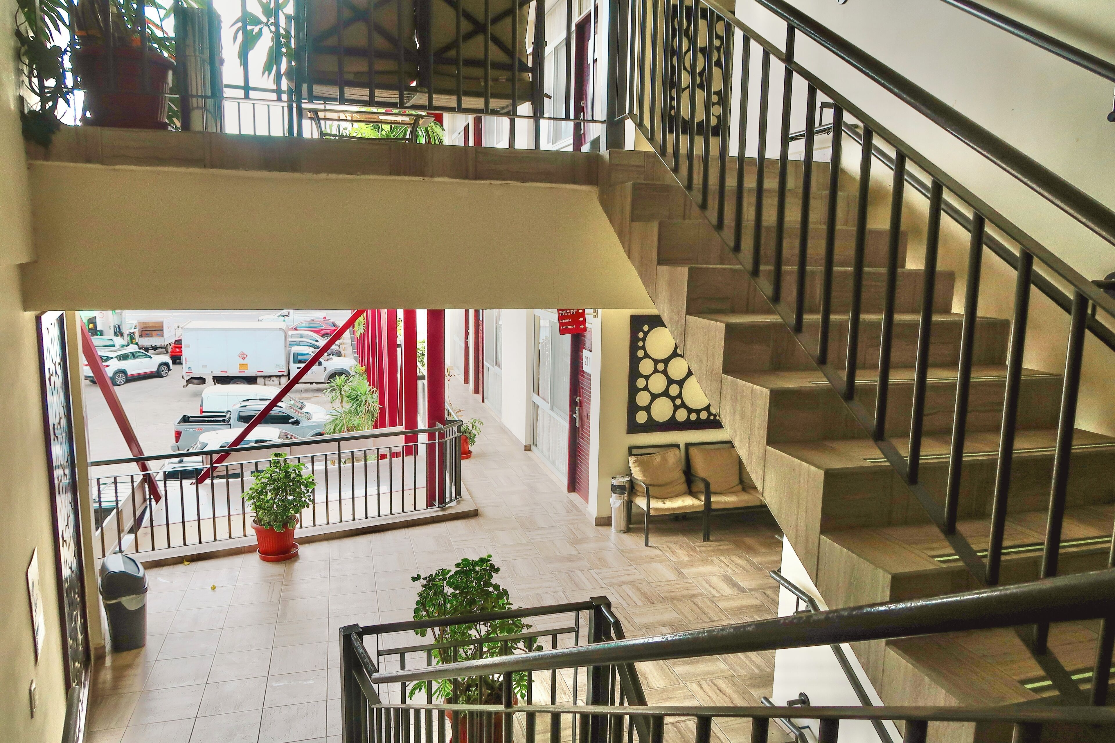 A multi-level interior with a staircase, potted plants, and a view of the street outside.