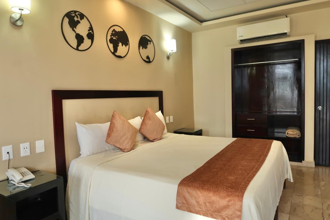 A hotel room with a large bed, a bedside table with a phone, and a wardrobe.