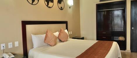 A hotel room with a large bed, a bedside table with a phone, and a wardrobe.