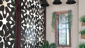 A bathroom with a modern design, featuring a patterned wall, a sink with a mirror, and three pendant lights. - Hotel Yorio Inn (Tuxpan)