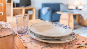 A dining table with a glass, plates, and a floral tablecloth.