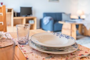 A dining table with a glass, plates, and a floral tablecloth.
