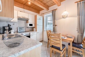 Une cuisine équipée d’un four à micro-ondes, d’une cuisinière, d’un évier et de chaises en bois autour d’une table.