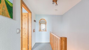 A hallway with a wooden door, a mirror, and a light fixture.