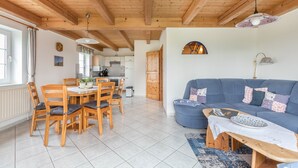 Un espacio habitable amplio con una mesa de comedor, sofá azul y vigas de madera en el techo.