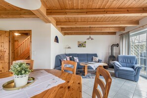 Un plafond en bois, un canapé, une chaise, une table et une fenêtre.