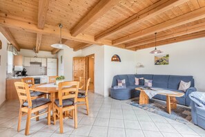 Un intérieur moderne avec une table et des chaises de salle à manger en bois, un canapé bleu et un coin cuisine.