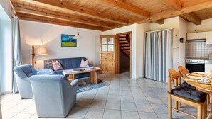 Uma sala de estar aconchegante com sofá, mesa de centro e mesa de jantar de madeira com cadeiras.