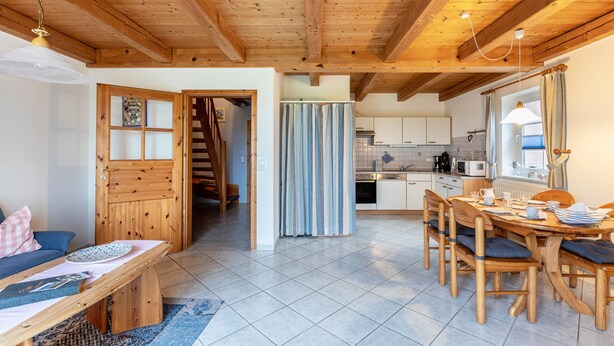 Interior em madeira com área de jantar, cozinha e escada.