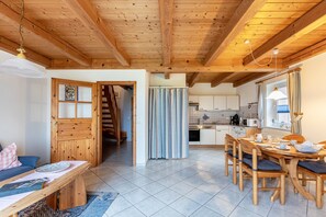 A wooden interior with a dining area, kitchen, and a staircase.