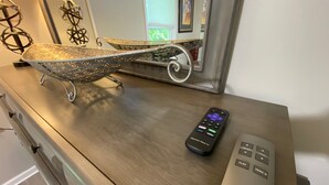 Une commode en bois, avec une télécommande et un objet décoratif posé sur le dessus.