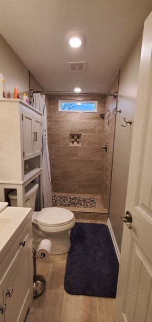 Ein Badezimmer mit Toilette, Dusche und einem kleinen Fenster.