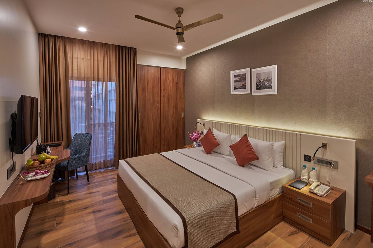 A hotel room with a bed, bedside table, desk, chair, and a ceiling fan.