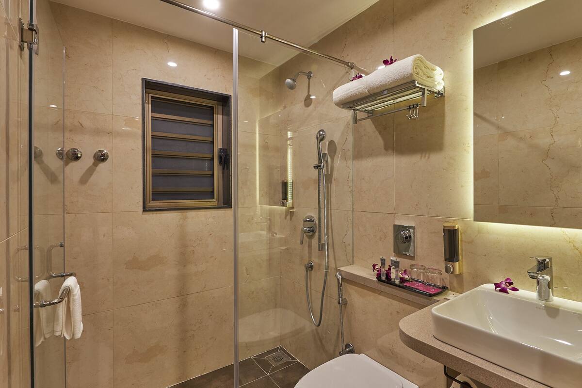 A modern bathroom with a glass-enclosed shower, a toilet, a sink, and a mirror.