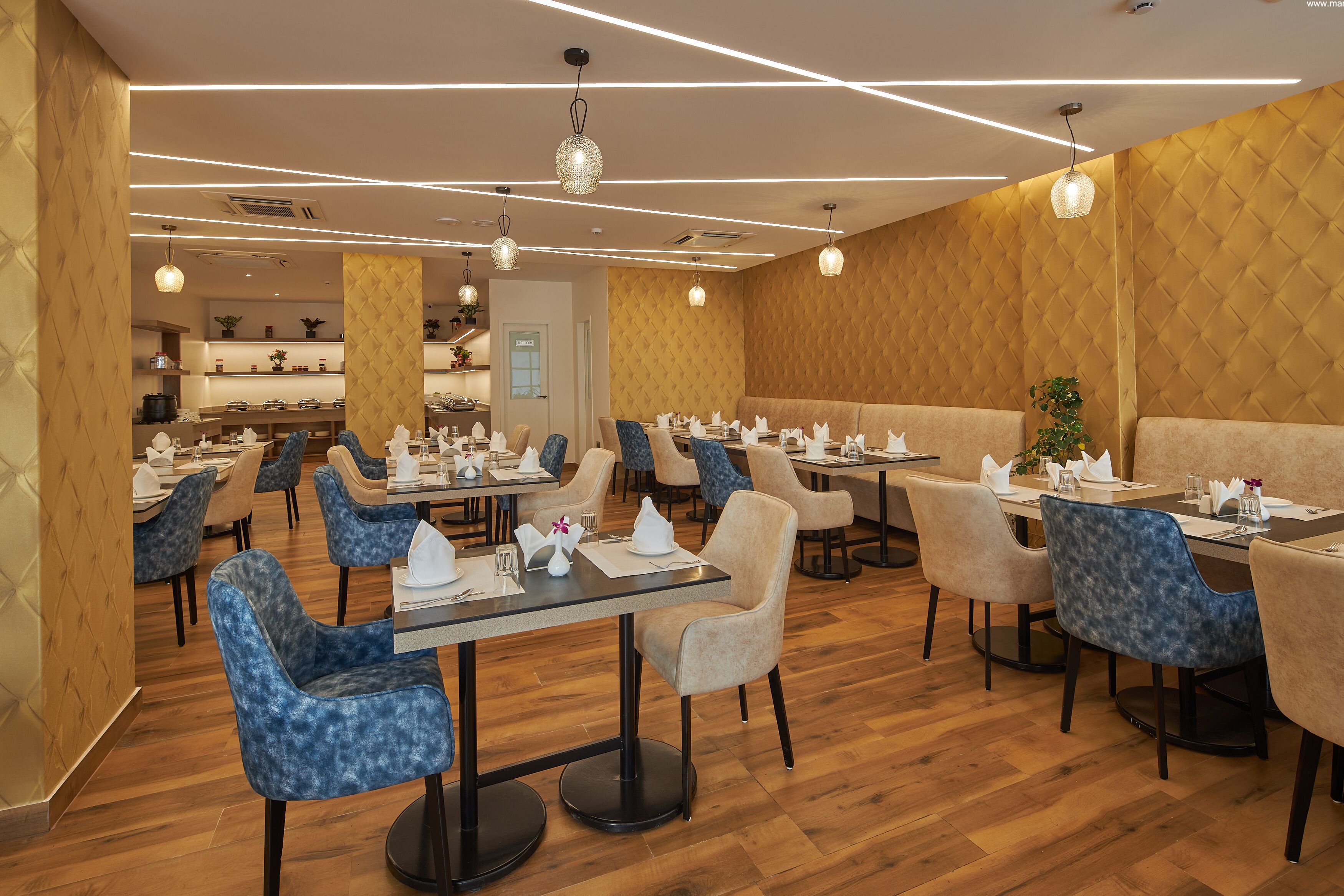 A restaurant with multiple tables and chairs, wooden flooring, and modern pendant lighting.