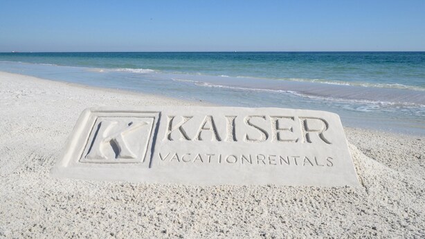 Een strand met een bord voor 'Kaiser Vacation Rentals' in het zand geëtst.