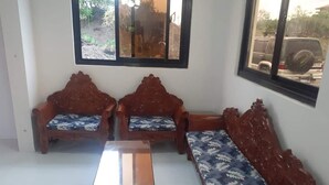 A room with a wooden sofa set, a matching bench, and a small table. - Family House to enjoy by the beach (Pasuquin)