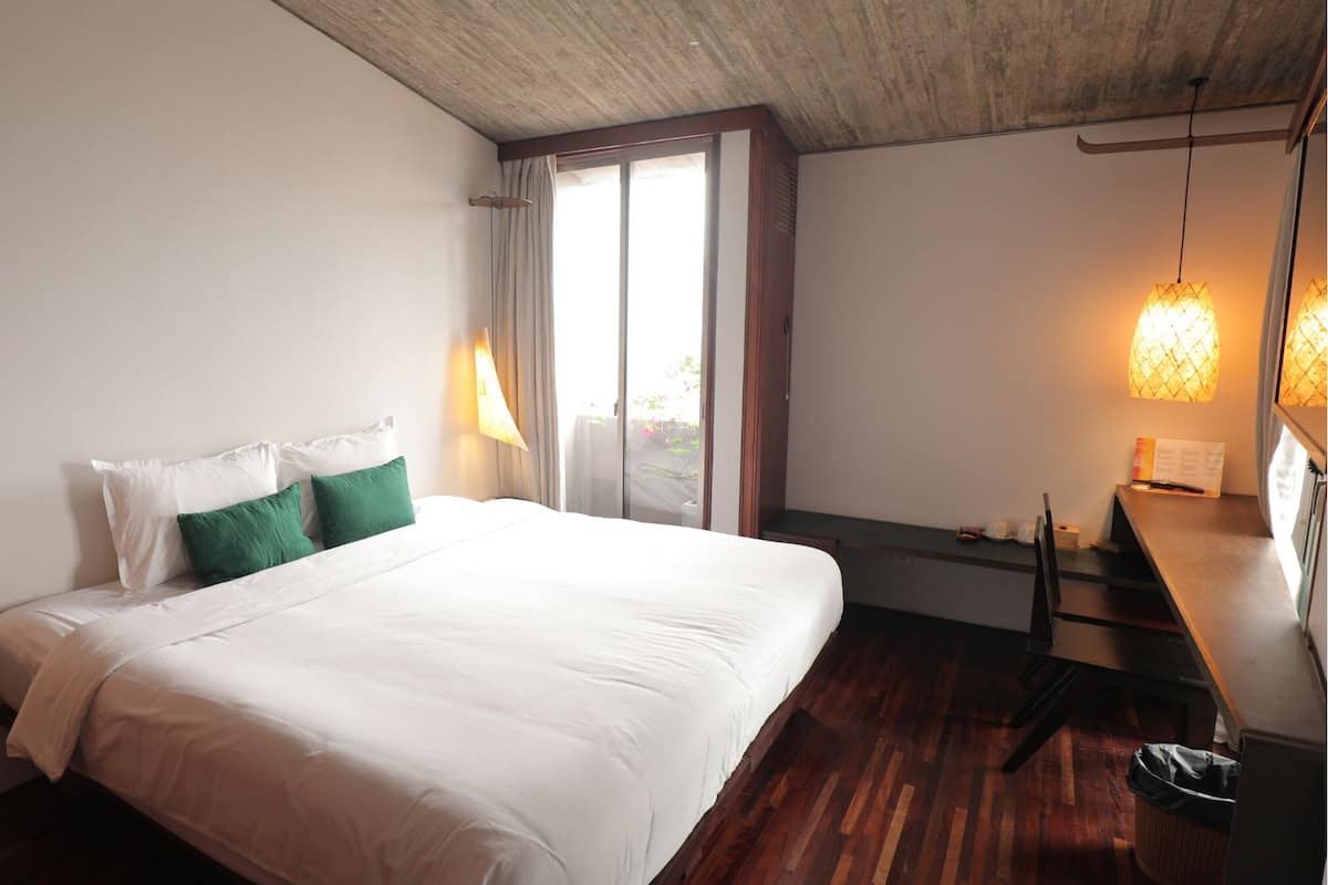 A bedroom with a bed, a desk, and a window.