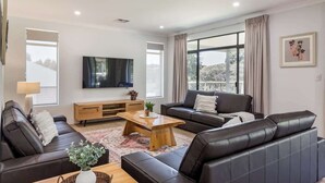 A modern living room with a sofa, coffee table, and TV. - Wildgreen Villa—Lakeside Hideaway in Winery Estate (Yallingup Siding)