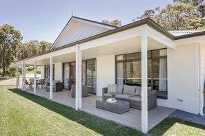 A modern house with a covered patio, outdoor seating, and a large window.