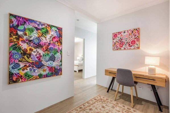 A room with a desk, chair, and two wall-mounted artworks.