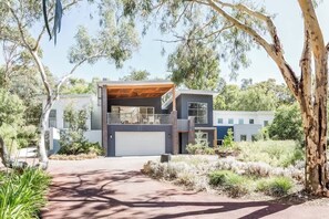 A modern two-story house with a garage, surrounded by trees and a landscaped garden. - Twintrees—A Family Escape Surrounded by Nature (Dunsborough)