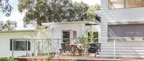 Una casa moderna con una terraza, mobiliario exterior y un ventanal grande.