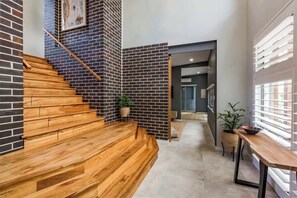 A staircase with wooden steps leading to a landing, a brick wall, and a door leading to another room.