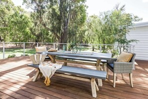 An outdoor deck with a picnic table and wicker chairs, surrounded by trees. - Twintrees—A Family Escape Surrounded by Nature (Dunsborough)