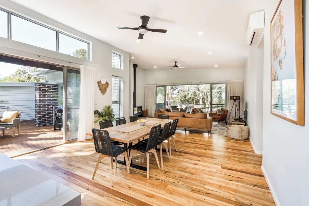 A spacious living area with a dining table, sofas, and a ceiling fan.