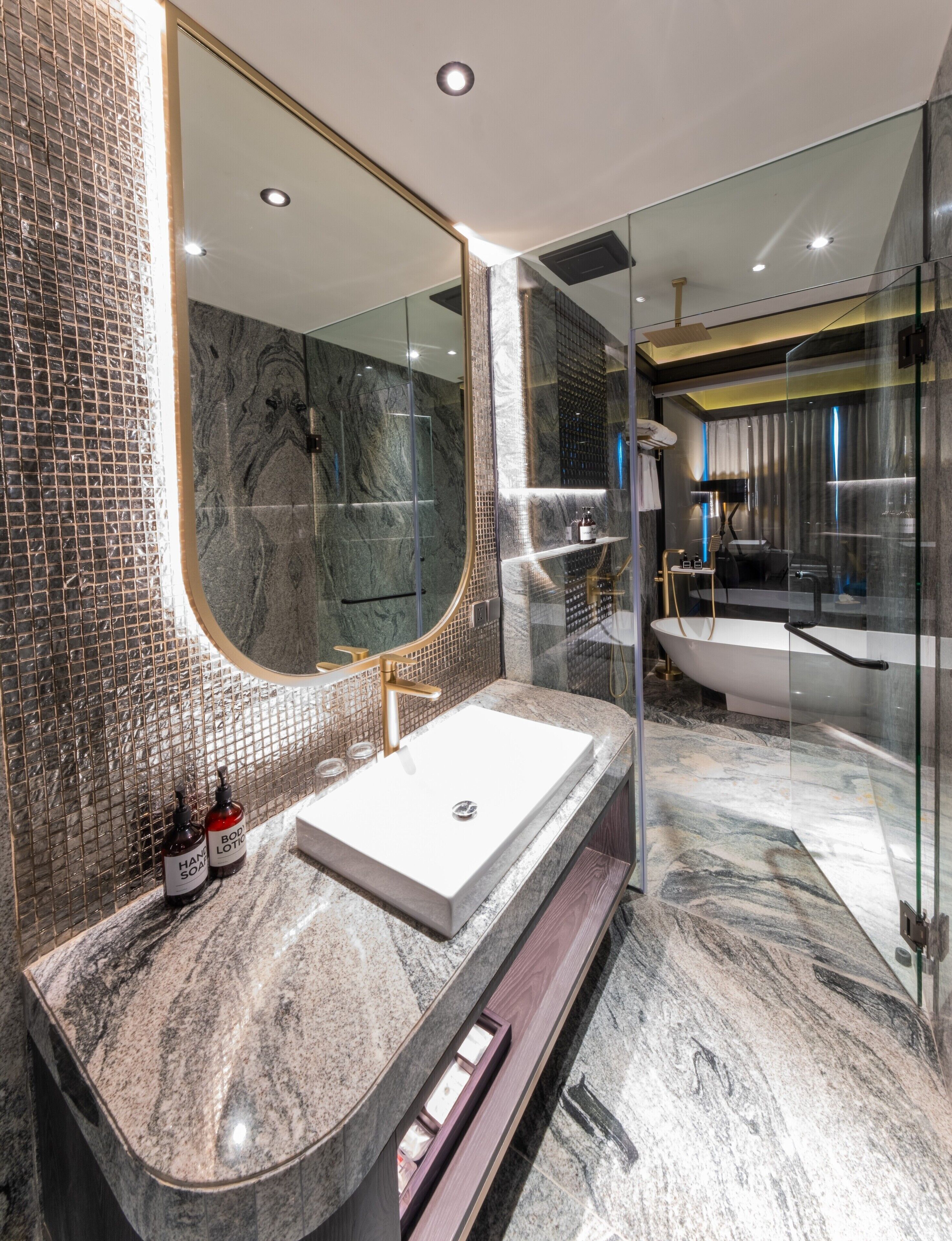 A modern bathroom with a marble sink, a large mirror, and a glass-enclosed shower area.