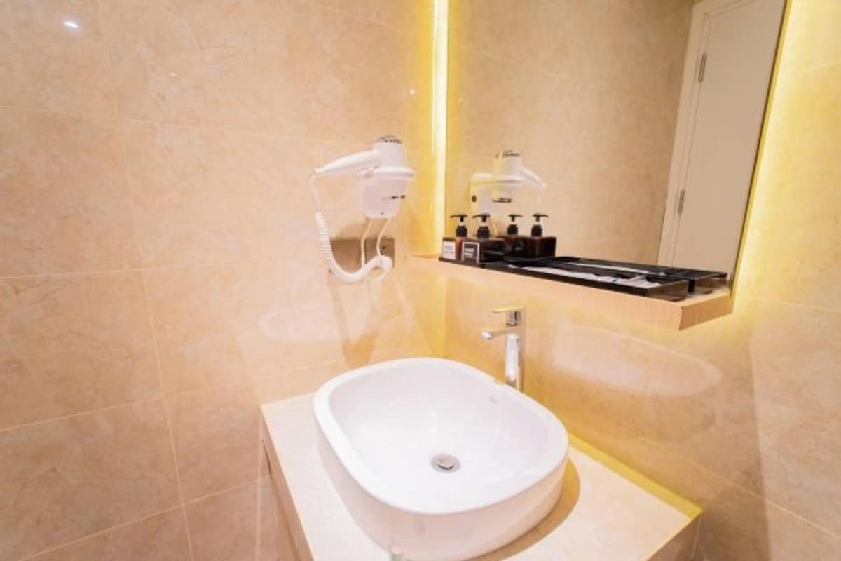 A modern bathroom with a white freestanding sink, a mirror, and a shelf with toiletries.