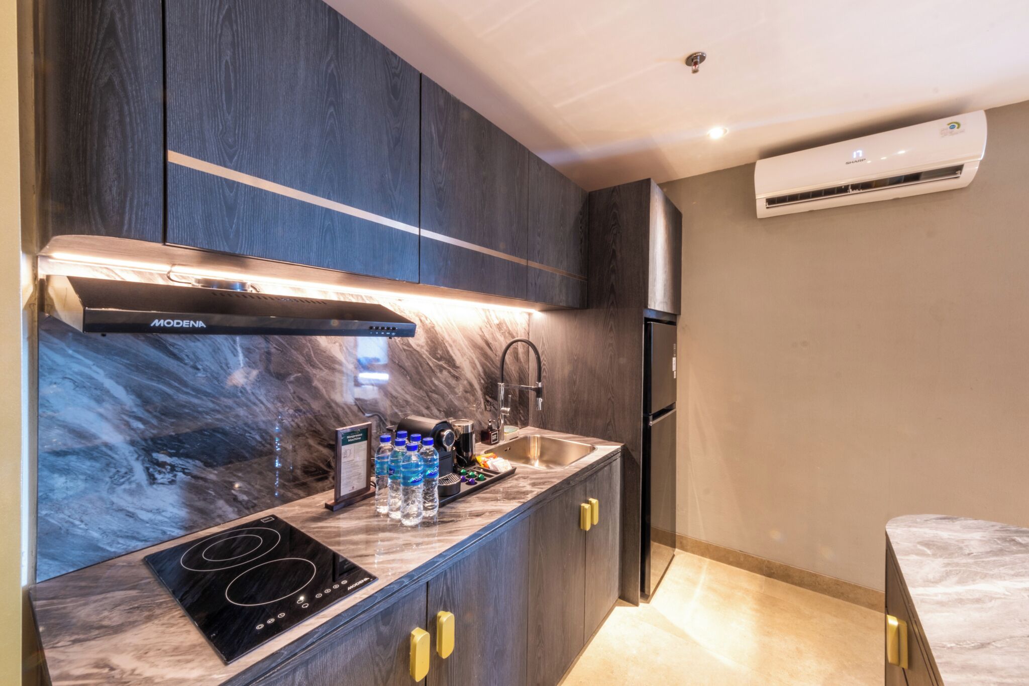 Una cocina moderna con armarios de madera oscura, estufa integrada y pileta de acero inoxidable.