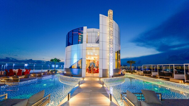 Een modern hotel met een zwembad, ligbedden en uitzicht op zee.