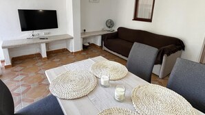 A living room with a TV, sofa, and a dining area with placemats and candles. - Bungalow 2 bedrooms for 5 people with swimming pool in Holiday Park urbanisation (Denia)