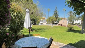 A patio with a round table and chairs, surrounded by a lawn and various plants. - Bungalow 2 bedrooms for 5 people with swimming pool in Holiday Park urbanisation (Denia)