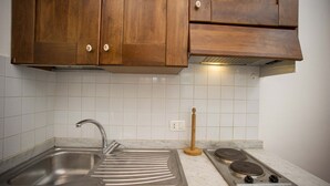 A kitchen with a stainless steel sink, a wooden rolling pin, and a gas stove. - RESIDENZA LA SCOGLIERA - MONO N° 2 LA SCOGLIERA (Rio Marina)